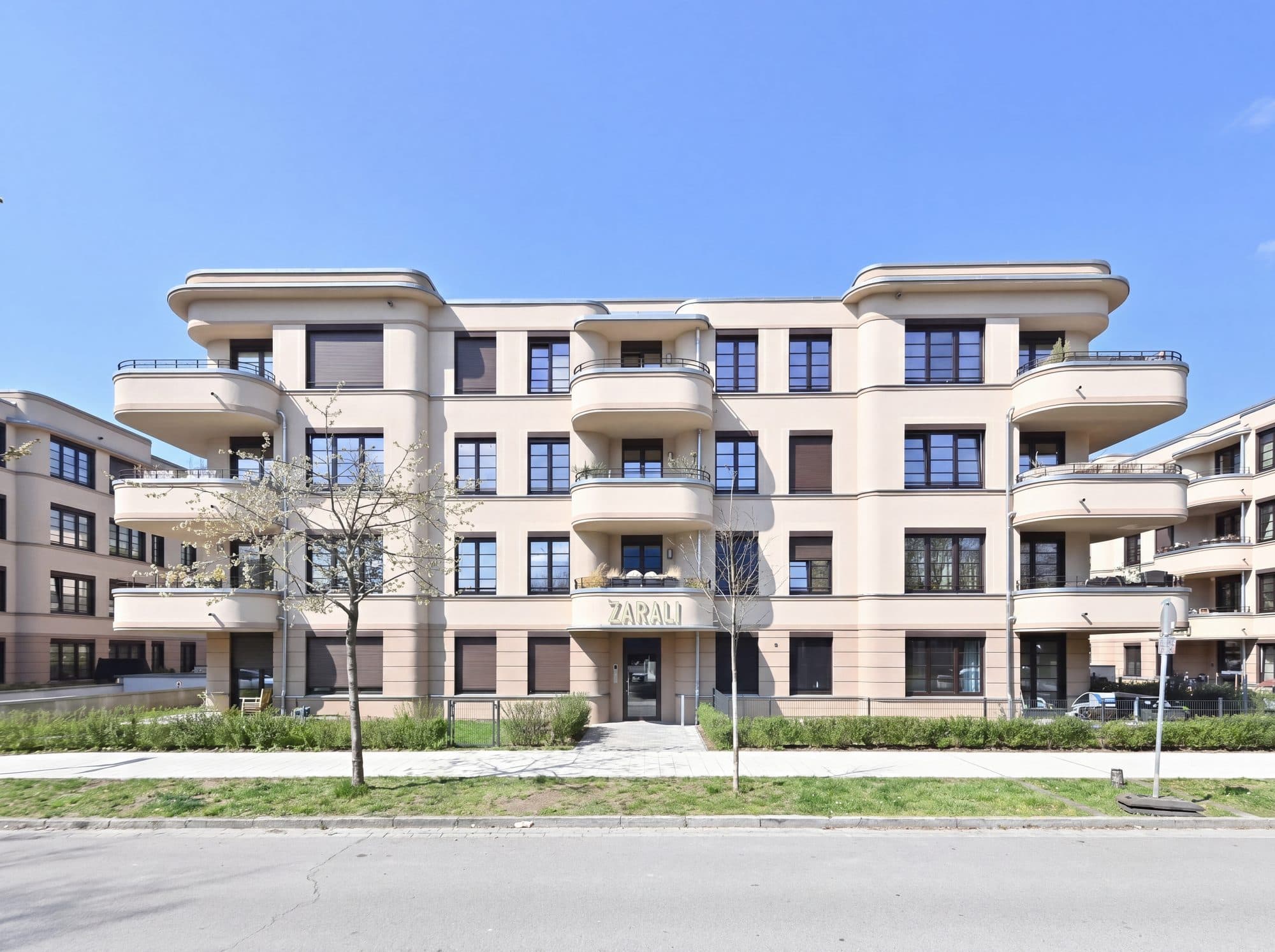 Fassade eines Neubaus mit geschwungenen Balkonen unter blauem Himmel