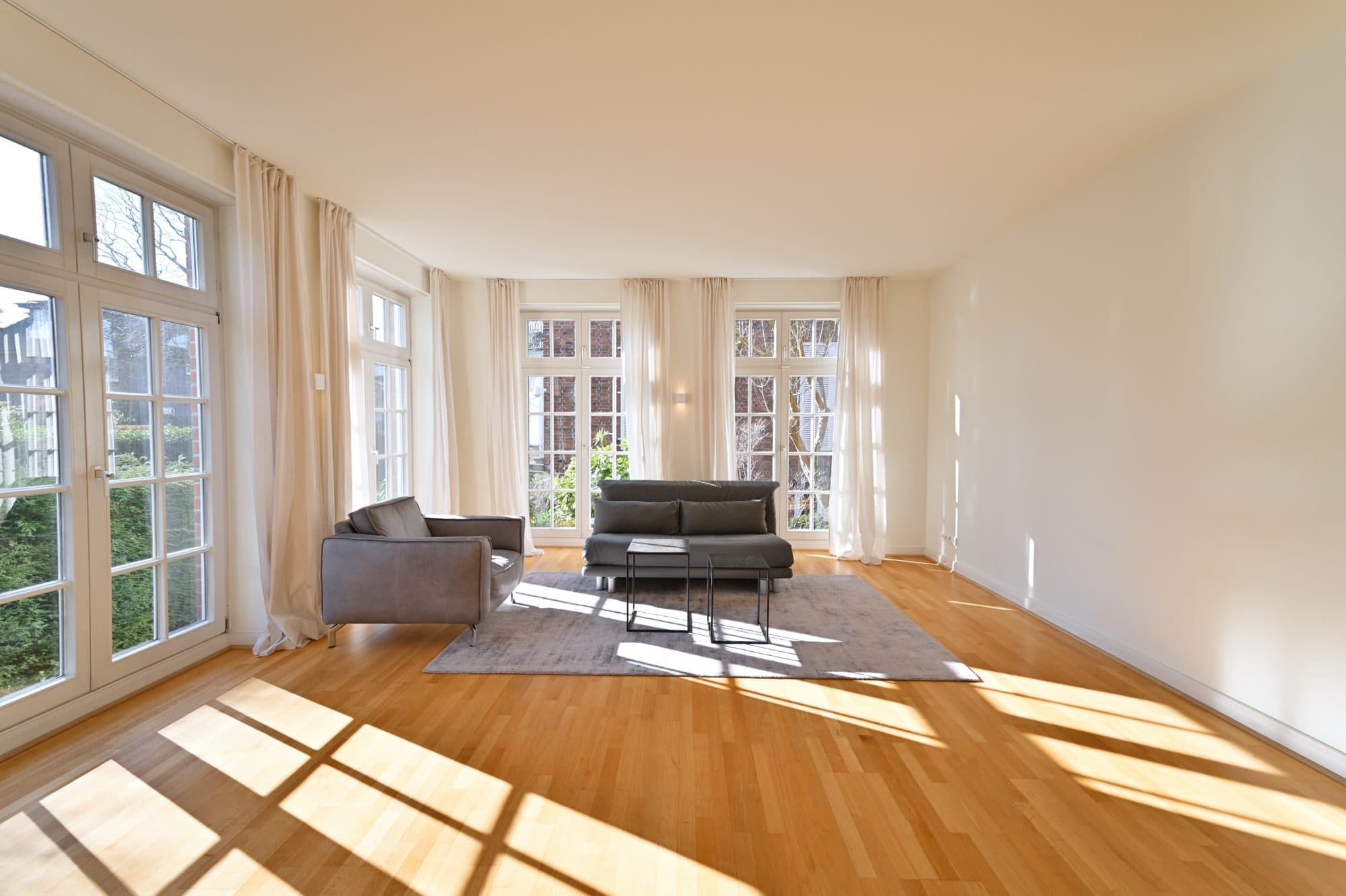 Sonniger Wohnraum mit Sprossentüren zum Garten und Ledersofa