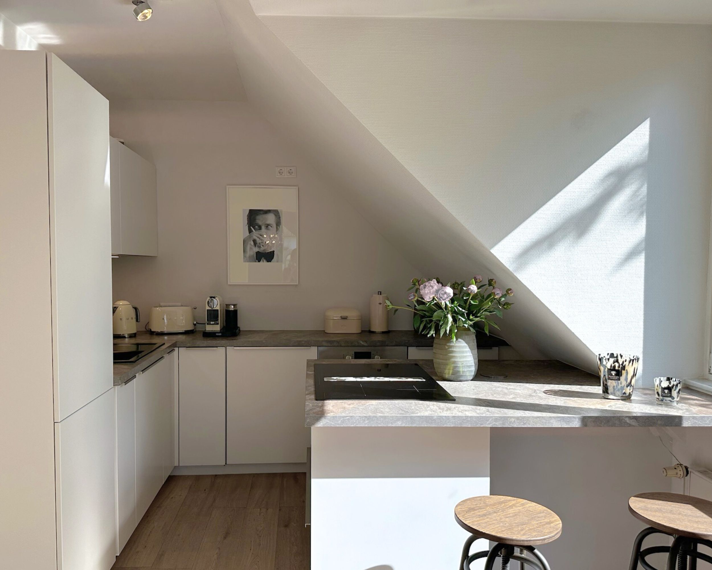 Moderne helle Küche mit Arbeitsplatte, Barhockern und frischen Blumen, fotografiert von Robert Schmieder – Immobilienfotografie Hamburg