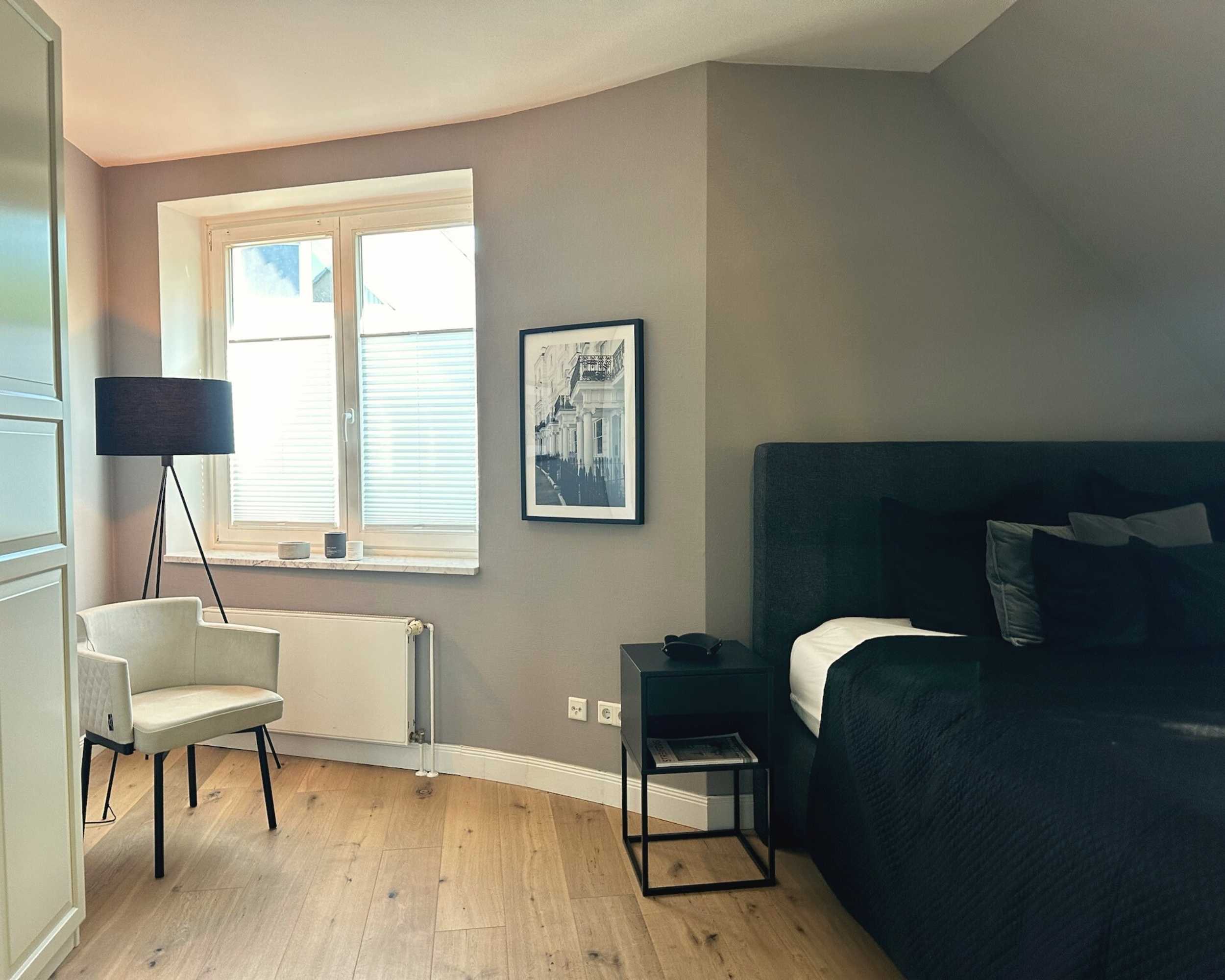 Modernes Schlafzimmer mit Doppelbett, Sessel und Stehlampe, fotografiert von Robert Schmieder – Immobilienfotografie Hamburg